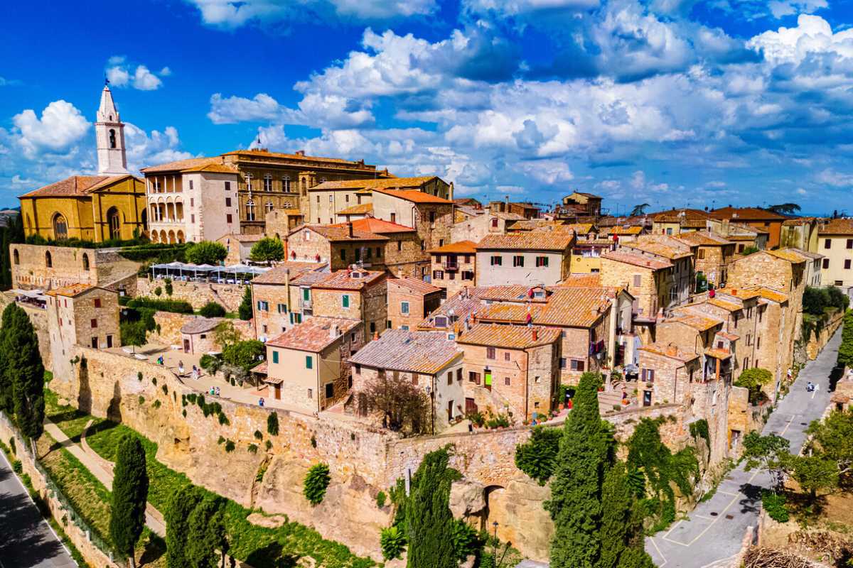 Vista panoramica di Pienza durante una festa tradizionale di paese, con striscioni colorati e gente nelle vie